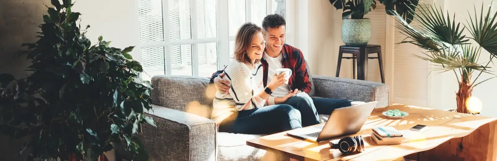 couple sitting on couch looking at their laptop